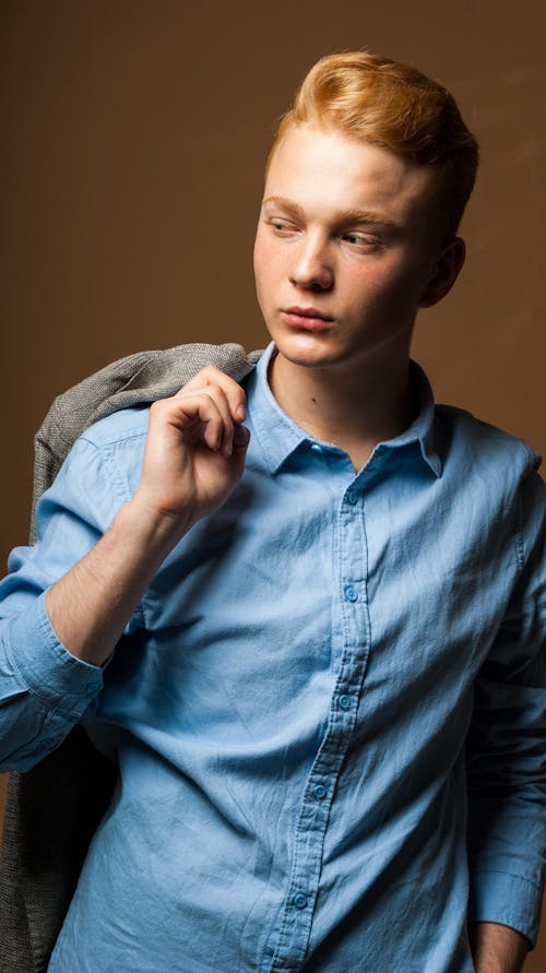 Young Redhead in a Blue Shirt and a Jacket Thrown over His Shoulder 