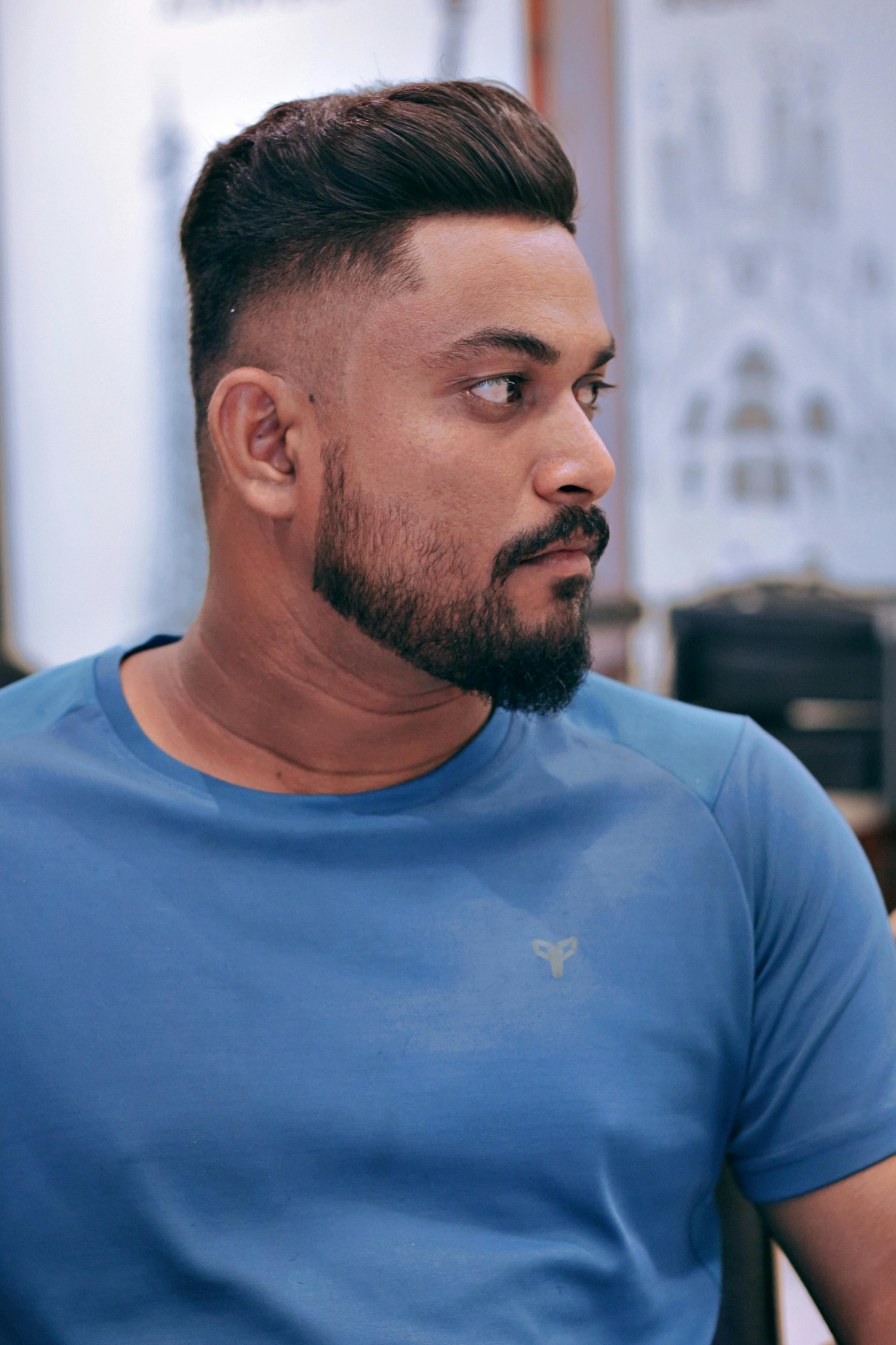 A close-up portrait of a man in casual attire looking to the side, indoors.