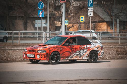 Free A vibrant sports car with graffiti artwork parked on an urban street corner. Stock Photo