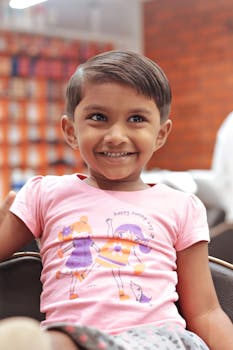 A cheerful child with a stylish short haircut, smiling in a salon.