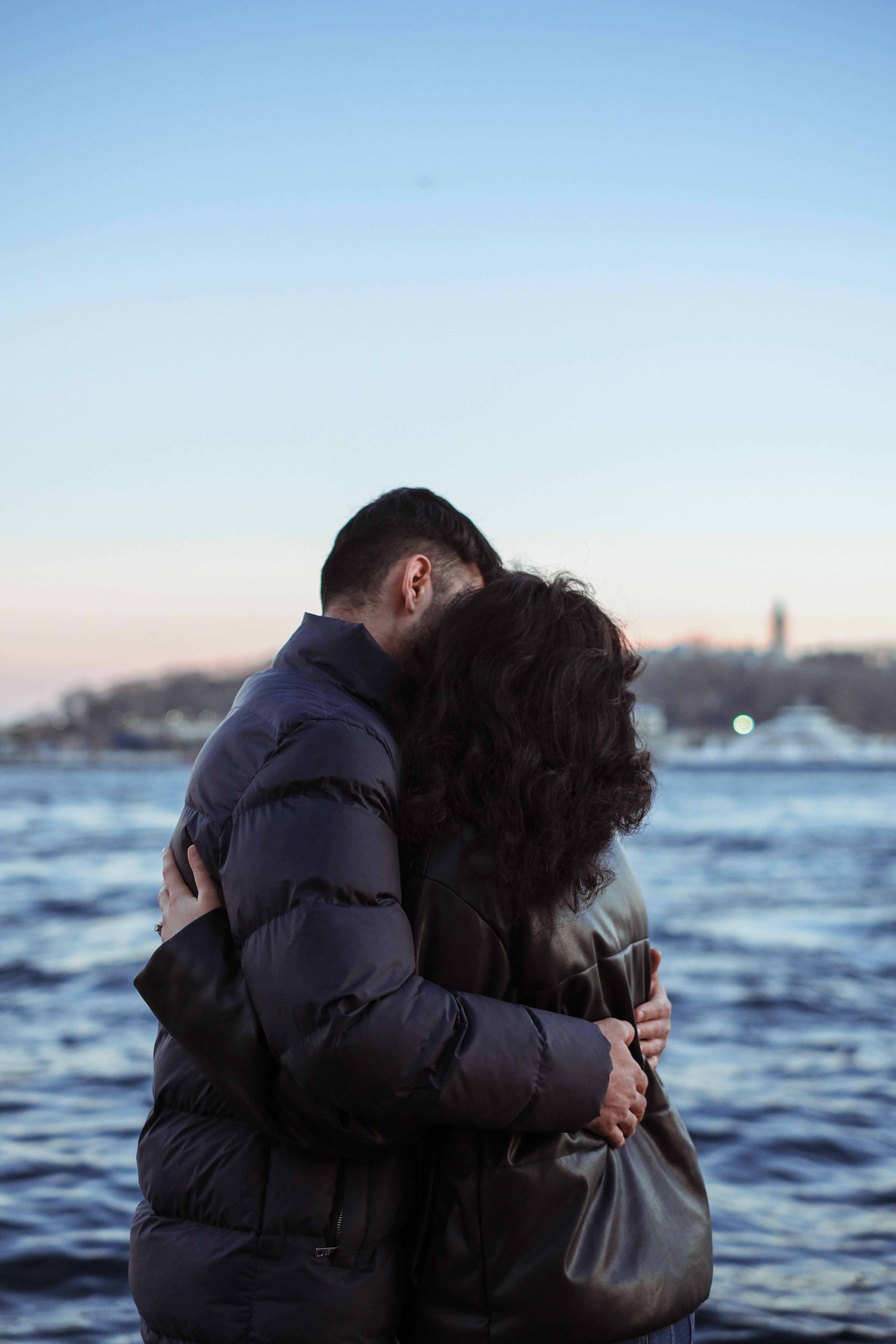 A couple embraces on a seashore, showcasing love and connection during twilight.