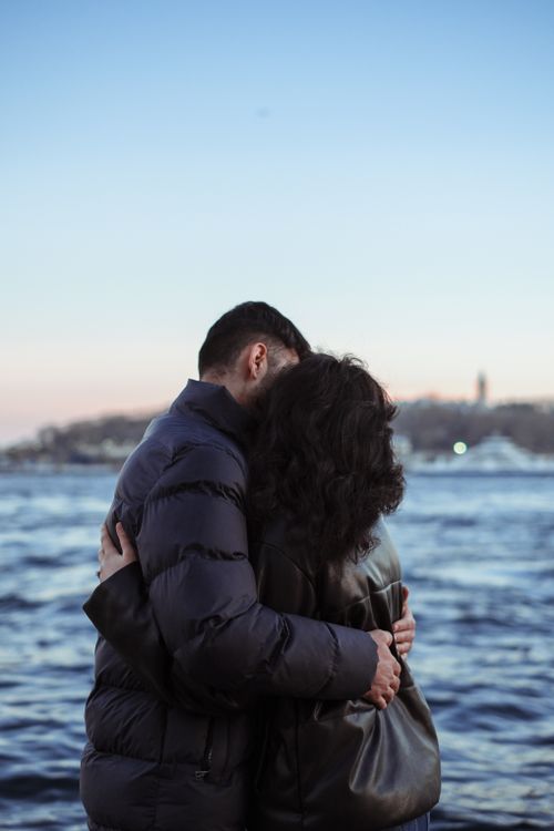 Free A couple embraces on a seashore, showcasing love and connection during twilight. Stock Photo