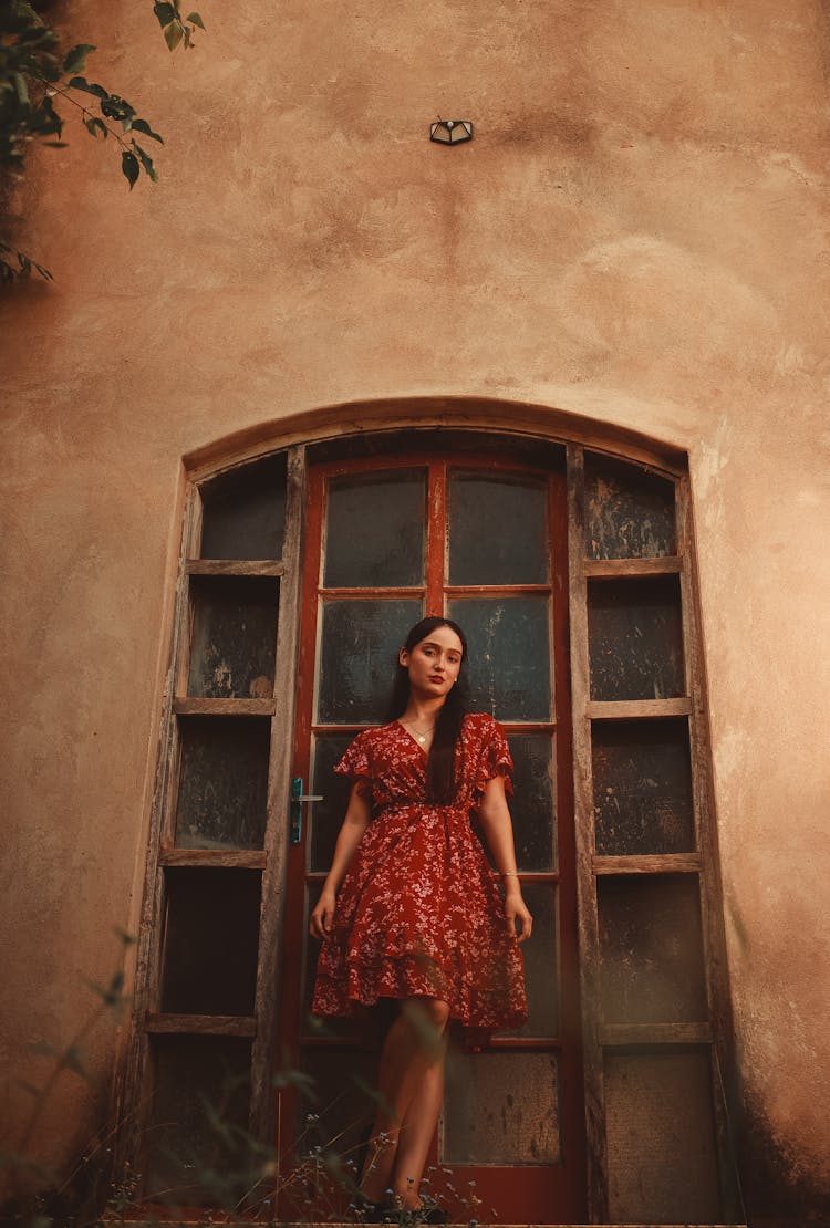 Woman In A Red Dress Standing In Front Of An Abandoned House 