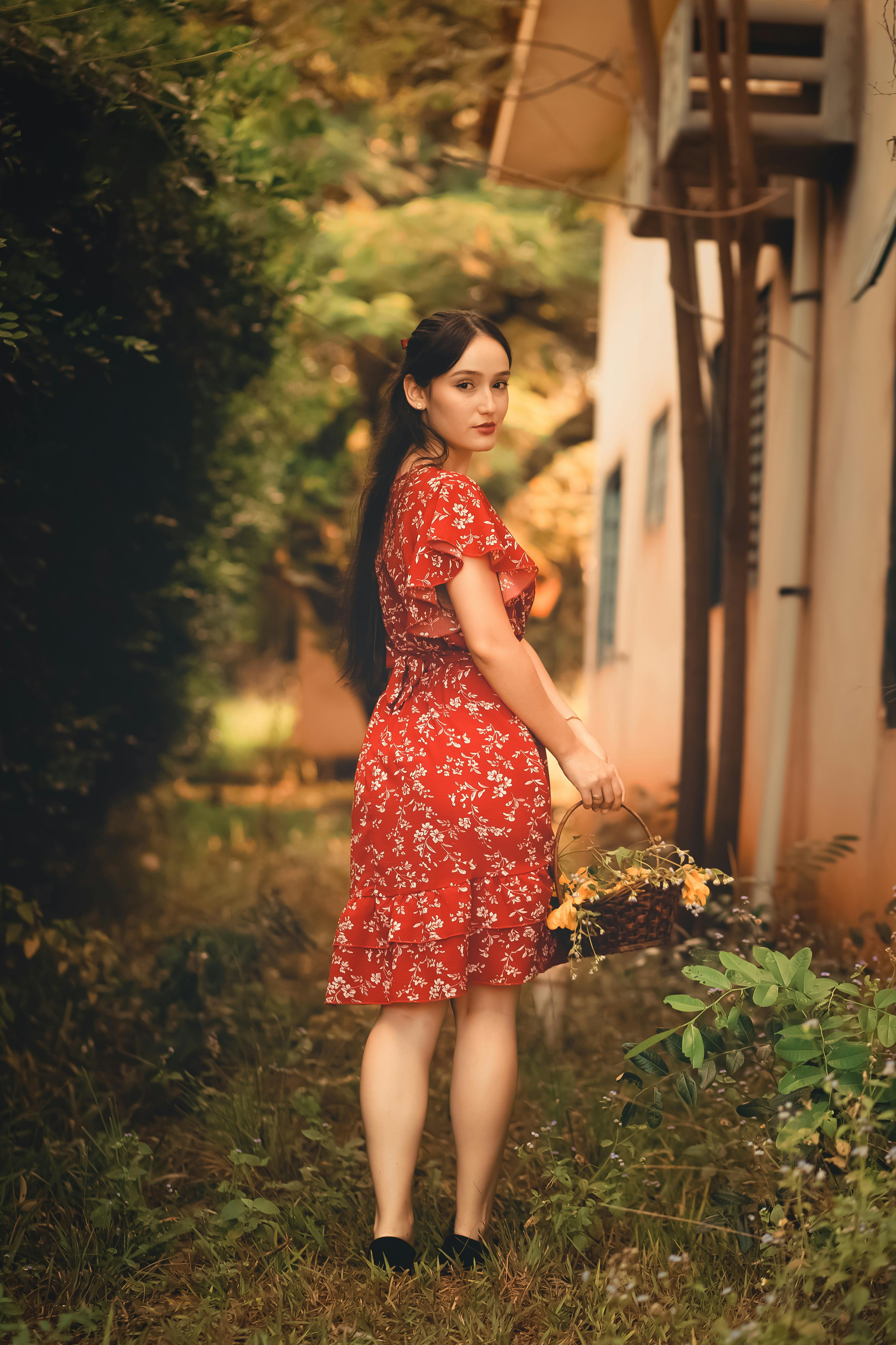 Free Elegant woman in red floral dress posing outdoors with flowers Stock Photo