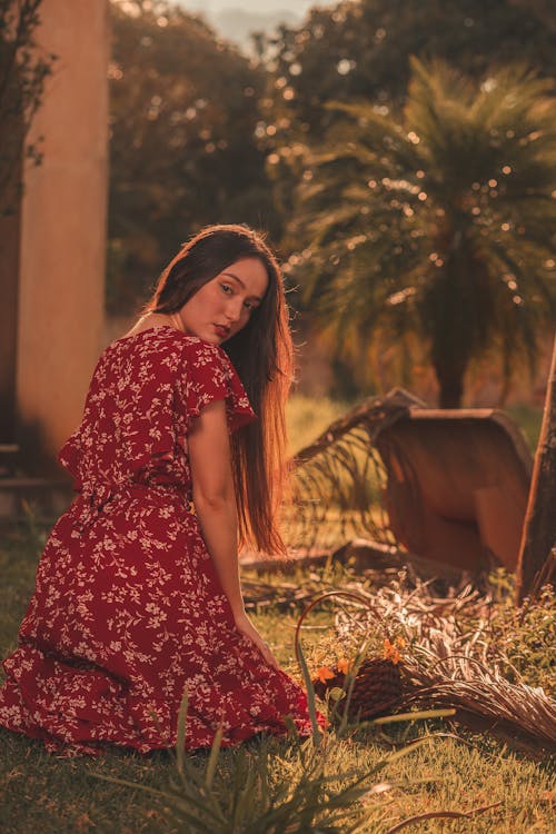 Woman in Red Dress Sitting on Grass and Posing