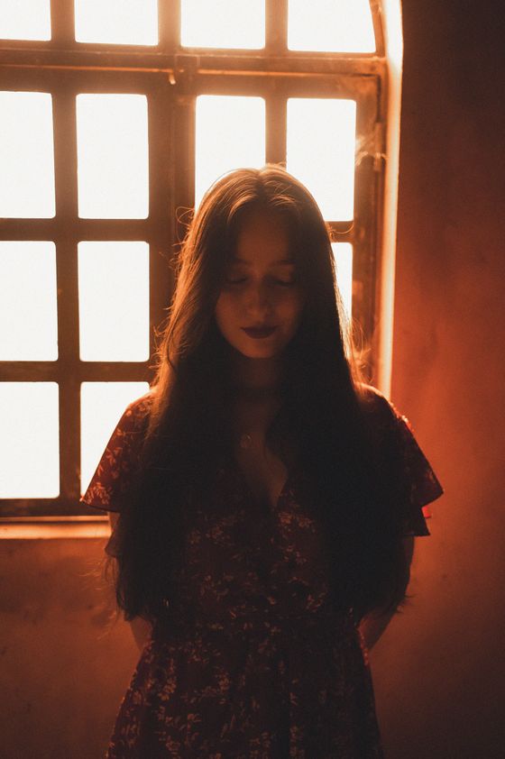 Amber window glow behind a still figure, photo by Breno Cardoso on Pexels
