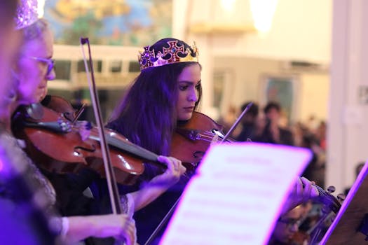 A woman in a crown plays violin during an indoor music performance.