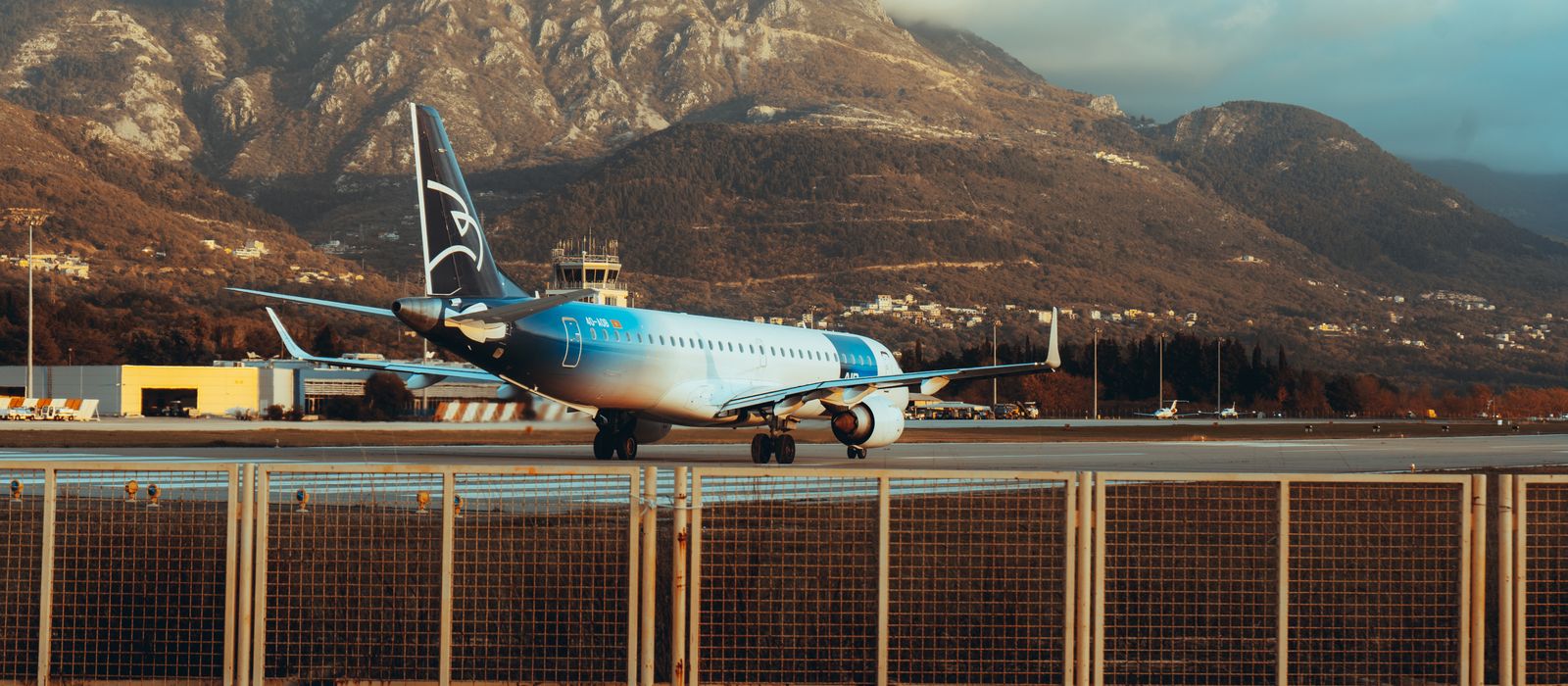 Airplane at Tivat Airport surrounded by stunning Montenegrin mountains during daylight. — flights from Belgrade to Tivat