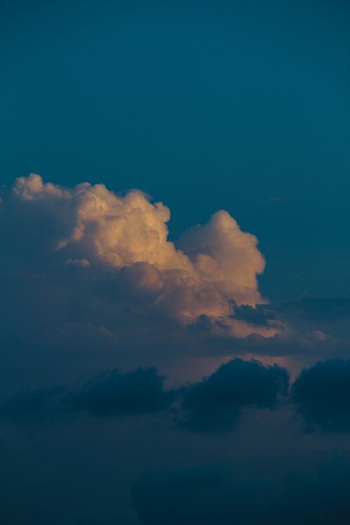 Free Moody clouds with sunset hues creating a dramatic sky scene. Stock Photo