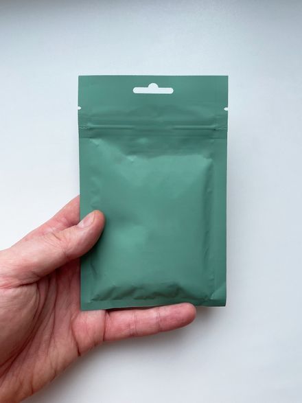 A green resealable storage pouch held up against a neutral backdrop — photo by Vitalii Abakumov on Pexels