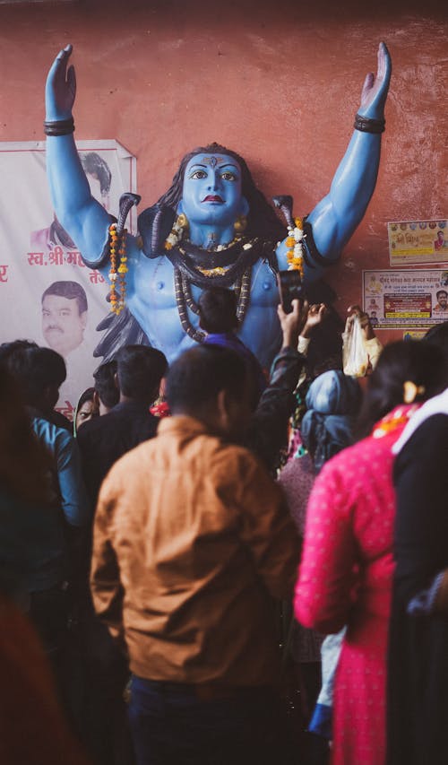 A Crowd Standing in front of a Statue of a Hindu Deity 