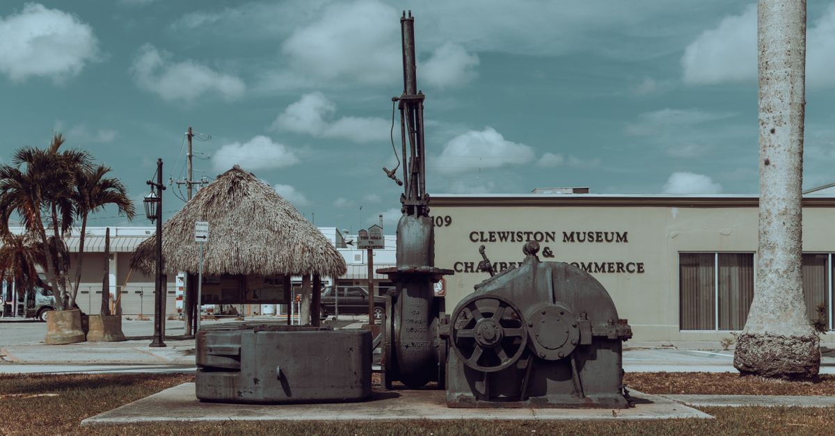 Vintage machinery with palm trees at Clewiston Museum entrance, Florida.
