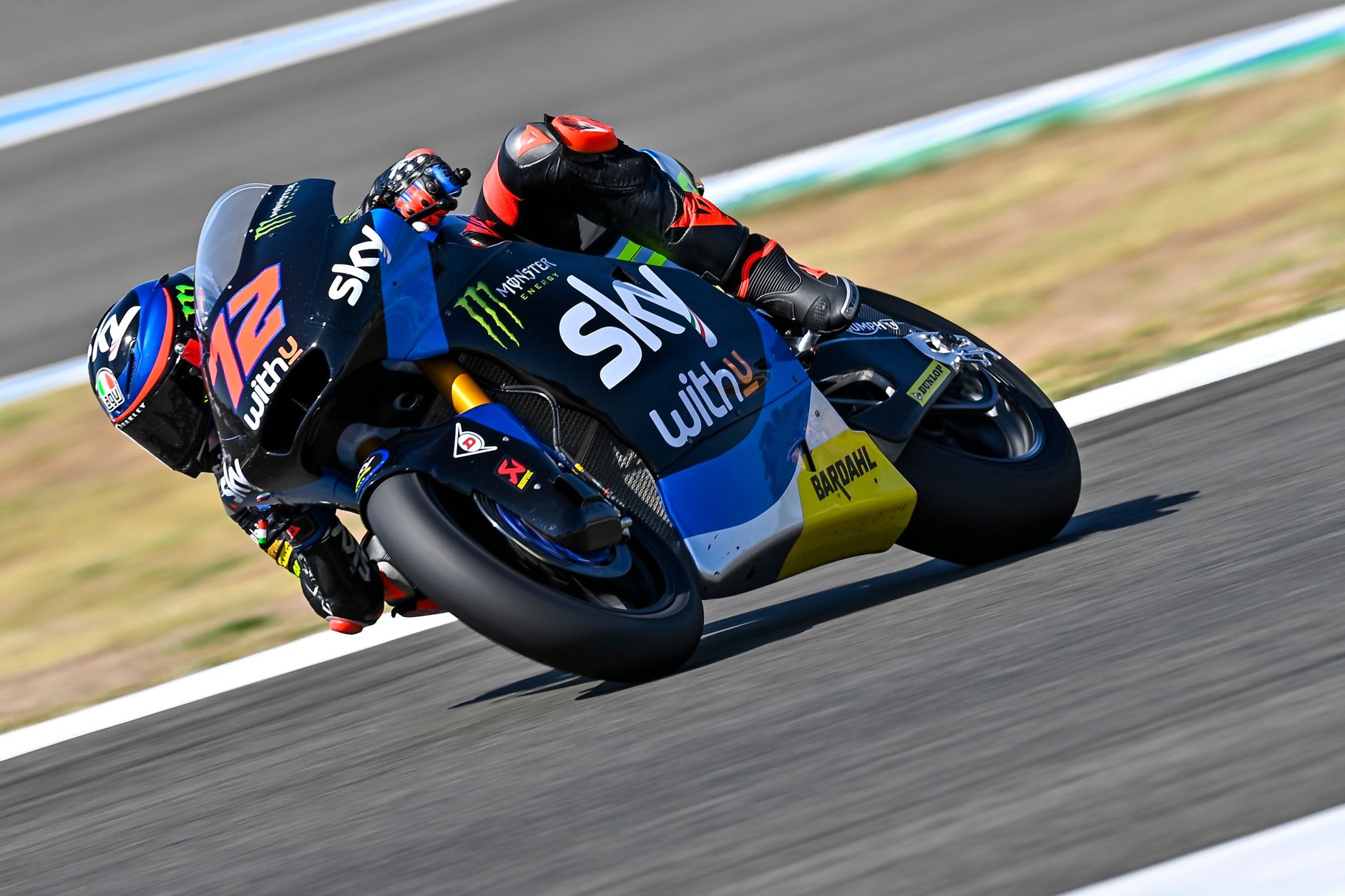 Dynamic capture of a motorcycle racing on an outdoor track with rider in sportswear.