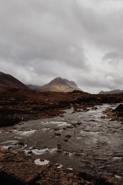 Capture of a moody Scottish Highland landscape featuring a flowing stream under overcast skies.