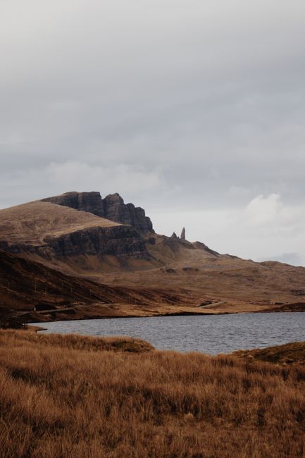Breathtaking view of the Old Man of Storr with surrounding grassy hills and loch in Scotland.