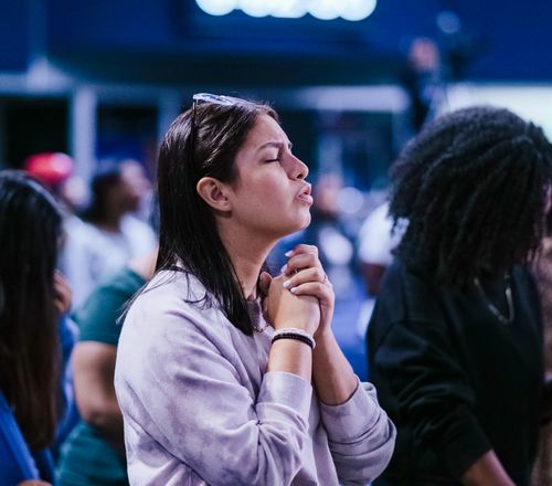 Free Pensive woman praying in a church with a crowd, expressing deep faith and spirituality. Stock Photo