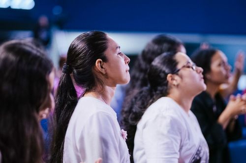 Free Individuals attentively engaged in a spiritual ceremony, capturing communal devotion indoors. Stock Photo