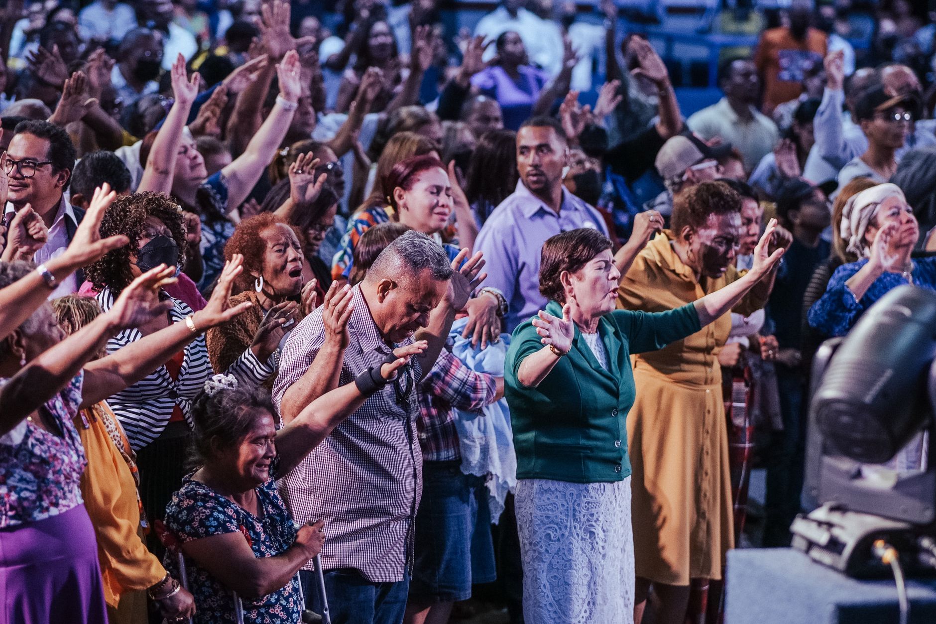 A diverse crowd engaged in spiritual prayer at an indoor community event.