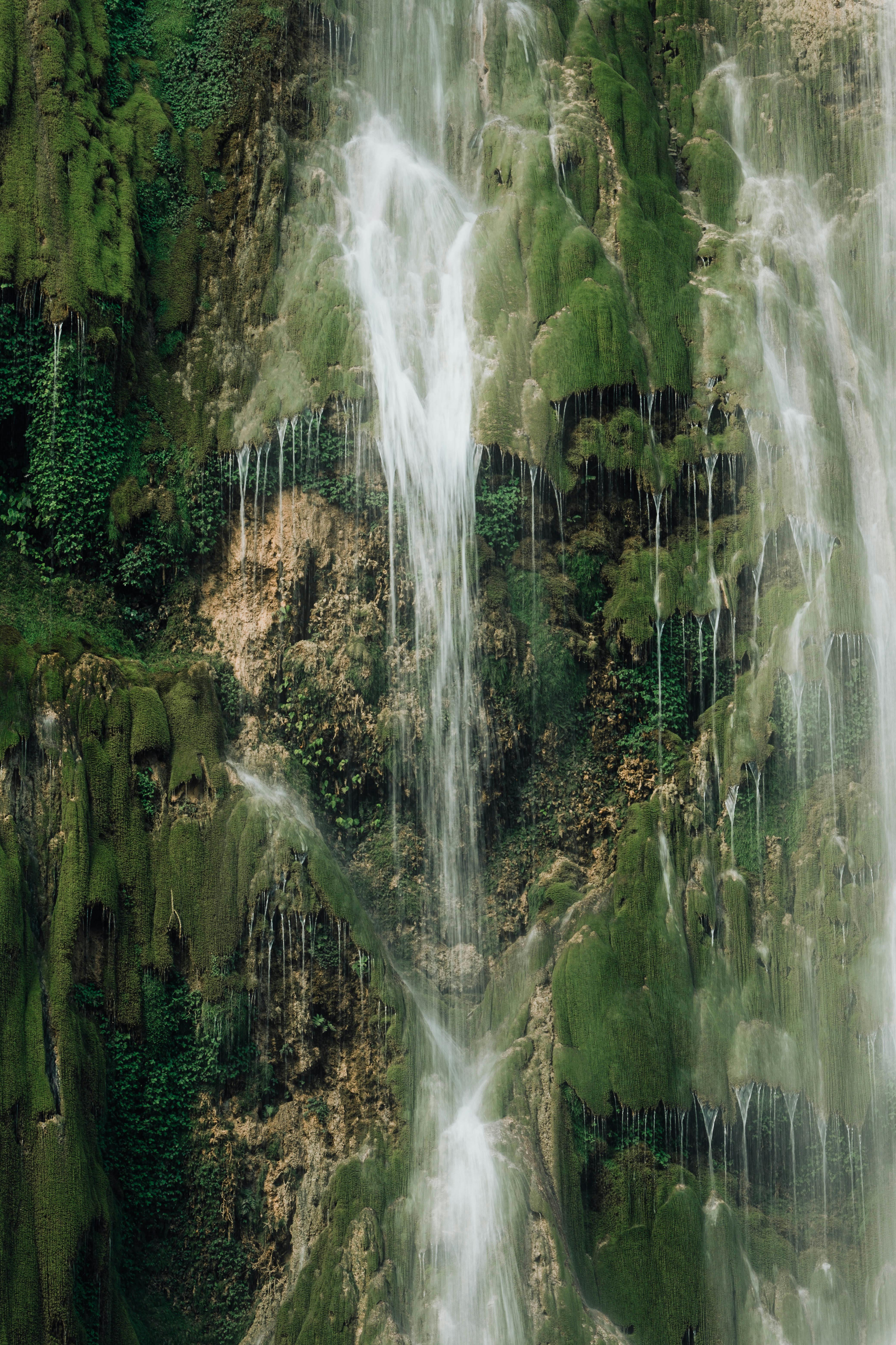 Beautiful waterfall cascading over moss-covered rocks in a serene natural setting.