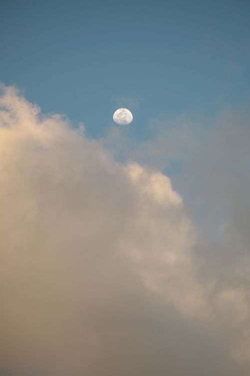 Free Captivating image of a full moon visible against a backdrop of clouds in the evening sky. Stock Photo