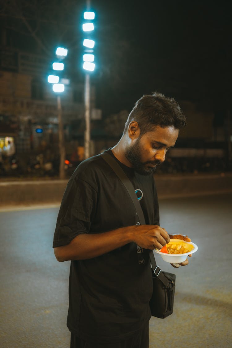 Man Eating On The Sidewalk