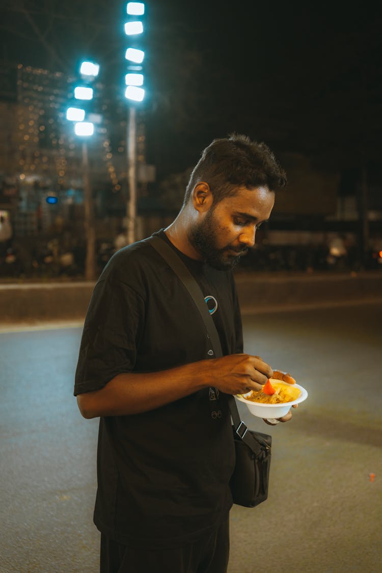 Man With Food In Bowl On Street At Night 