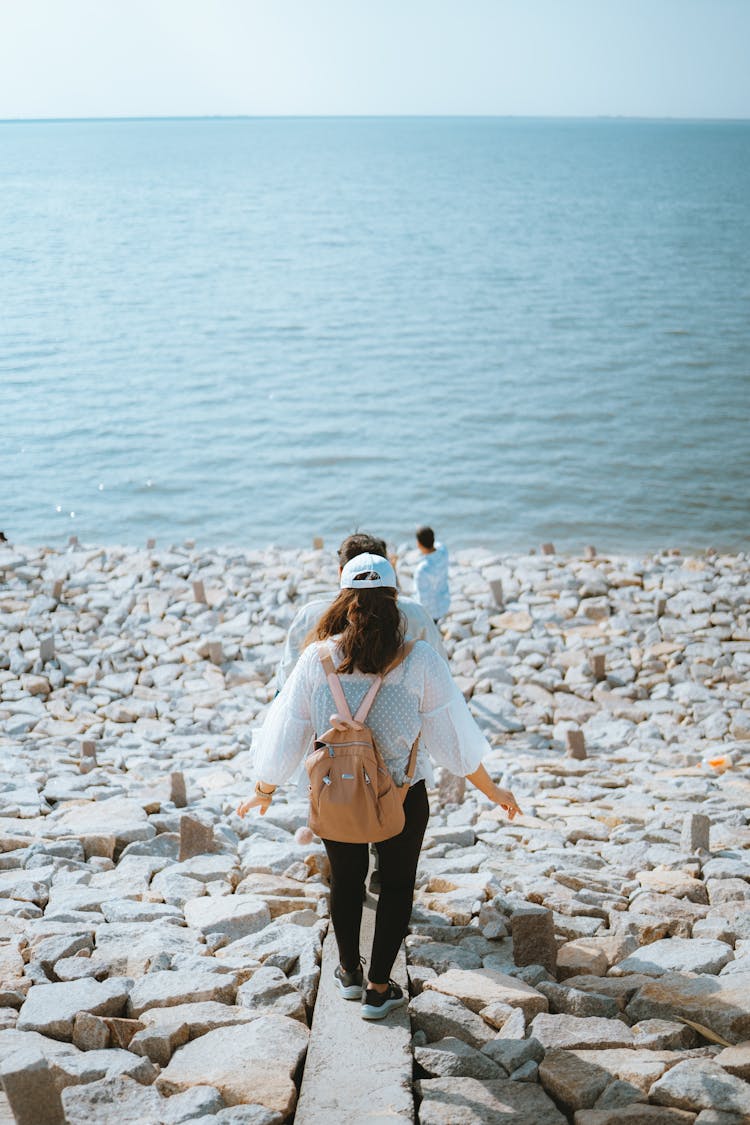 Couple Walking On Rocky Beach