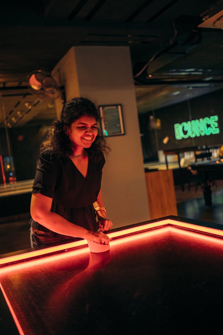 Young Woman Playing Air Hockey In A Bar