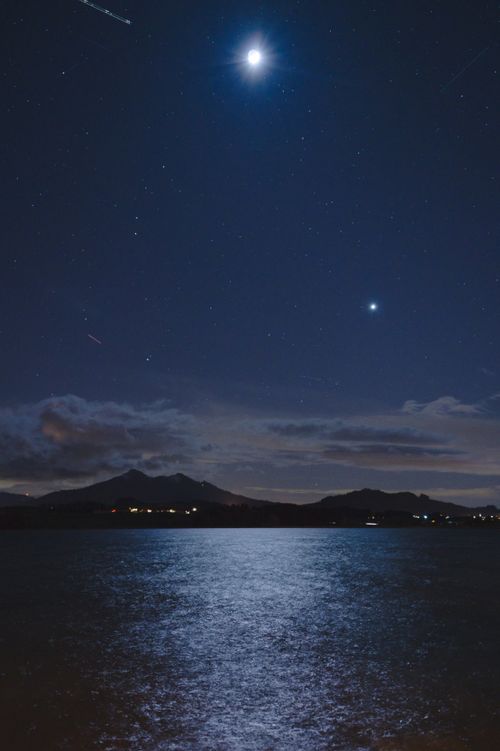 Free Captivating nightscape featuring a lake, moon, and starry sky creating a tranquil atmosphere. Stock Photo