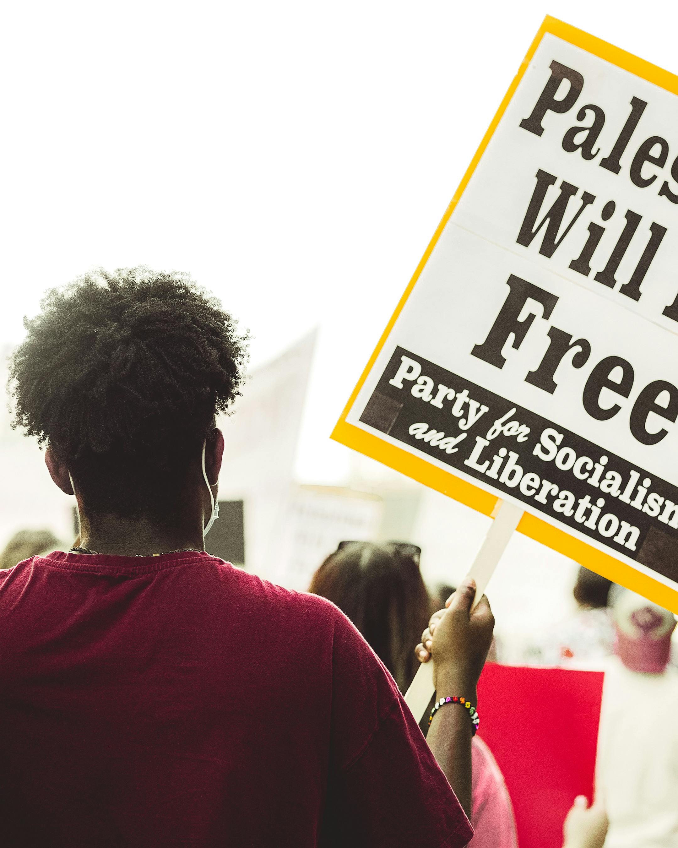 a person holding a sign that says palestine will be free