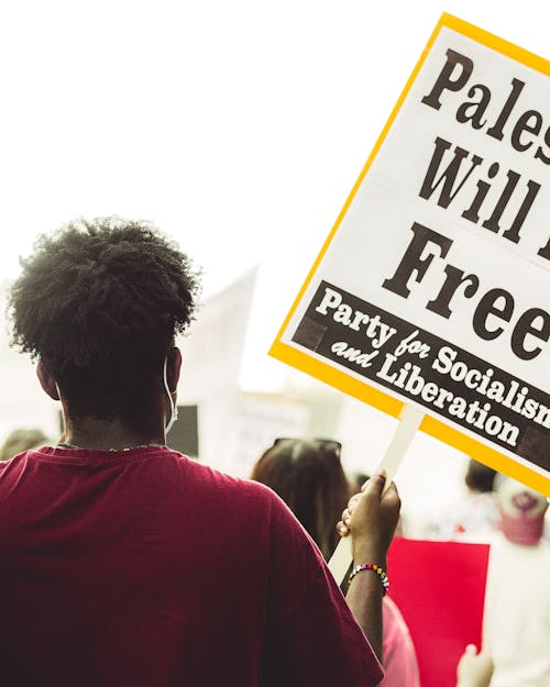 A person holding a sign that says palestine will be free