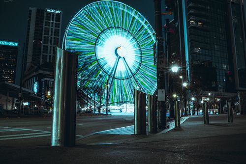 Free A glowing ferris wheel spins against a city skyline at night. Stock Photo