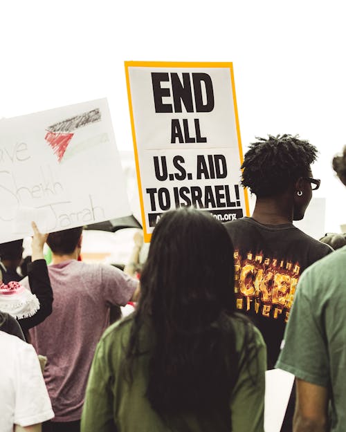 A group of people holding signs that say end all us and israel