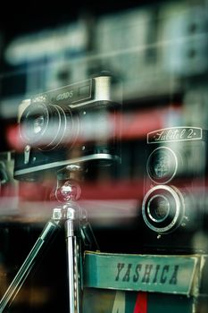 A showcase of vintage cameras behind glass in a retro-themed store display.