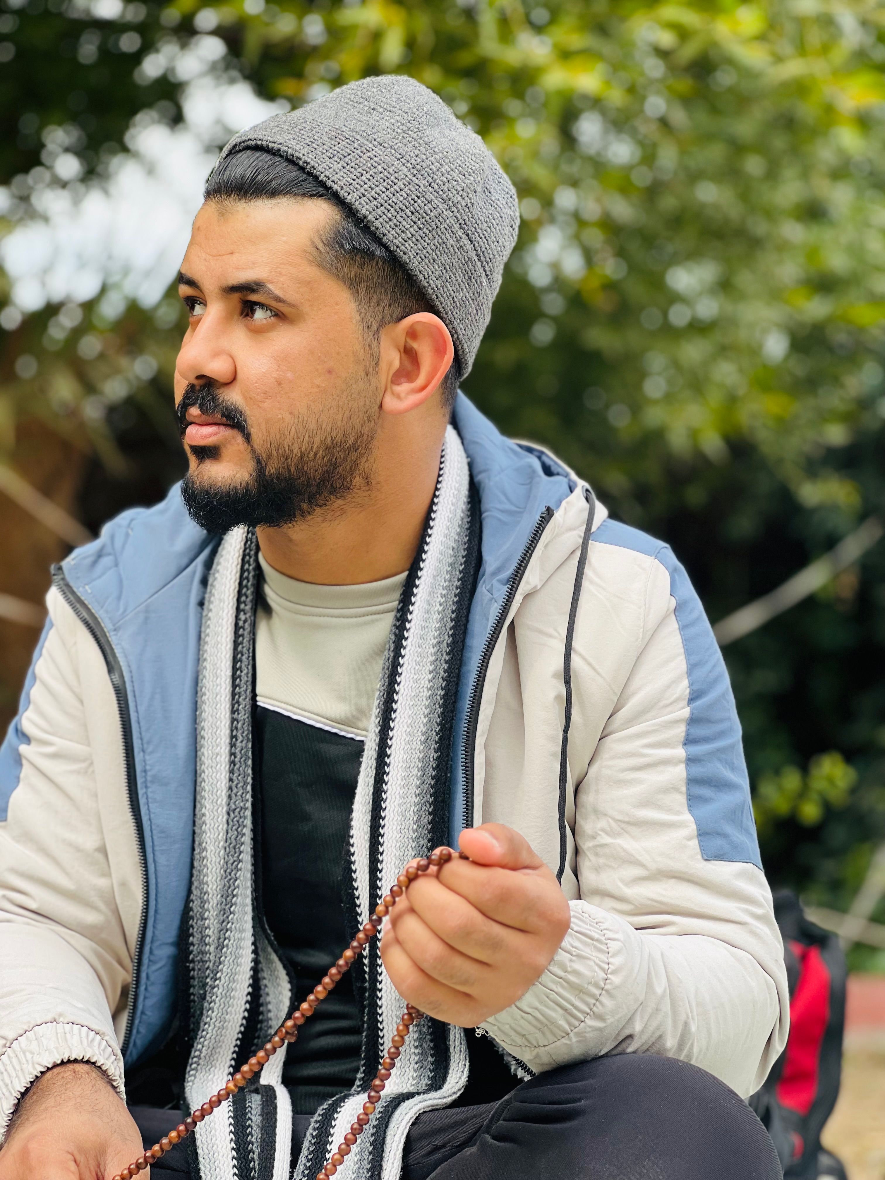 Man in casual attire holding prayer beads, emphasizing spirituality outdoors.