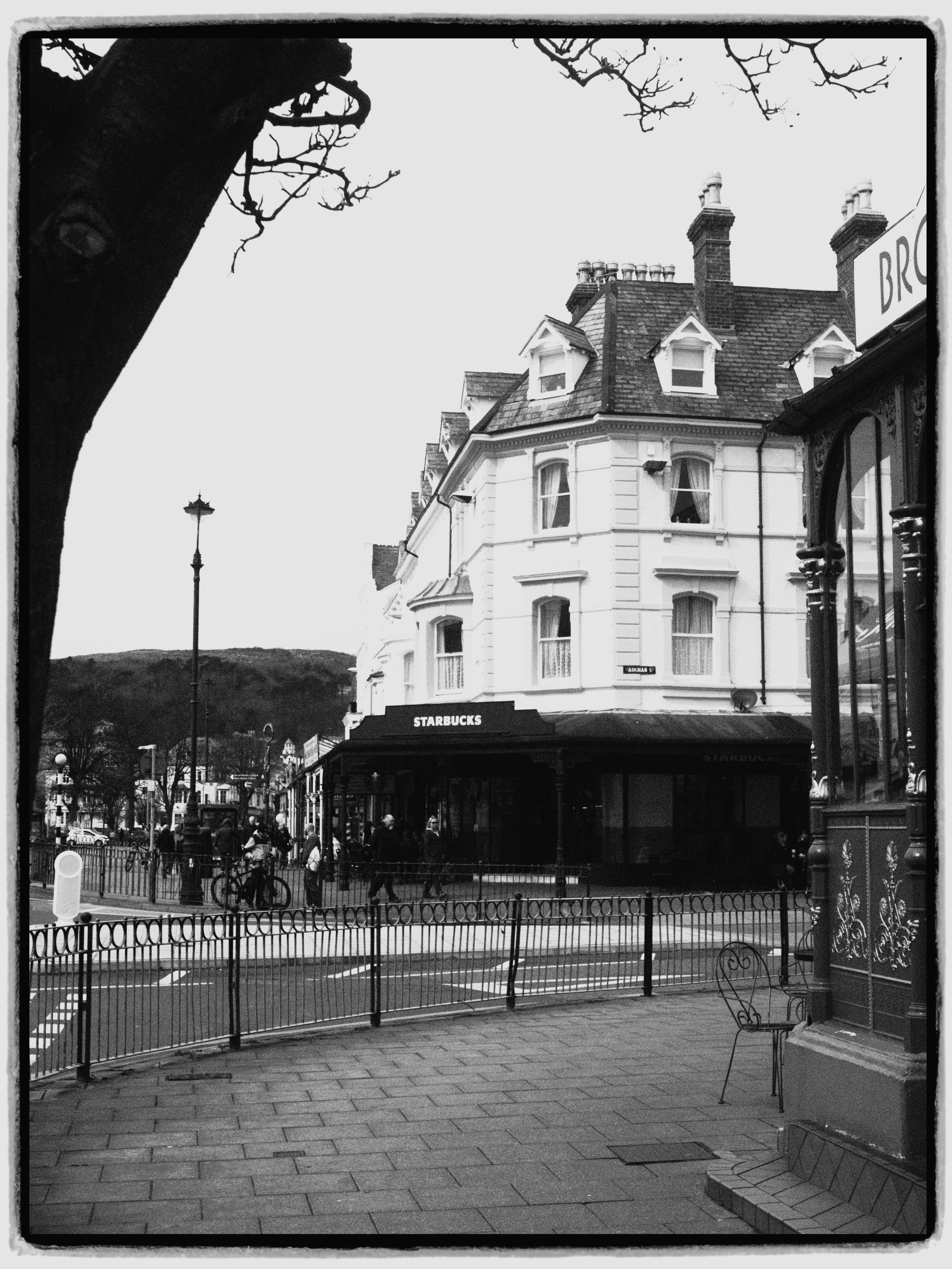 Black and white photo capturing an urban street with a historic building and sidewalk.