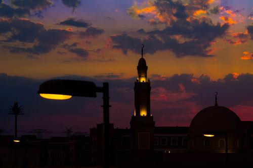 Free Silhouette of a mosque with a domed structure and minaret against a vibrant sunset sky in Dubai. Stock Photo