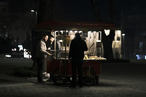Free Captivating night scene of street food vendors serving customers in an urban setting. Stock Photo