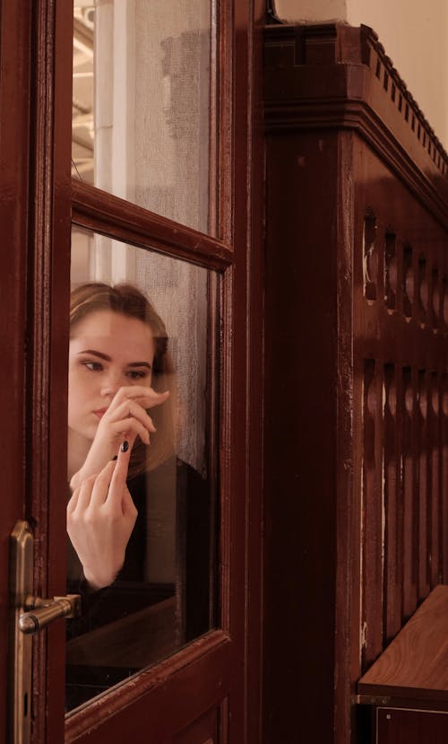 Young Woman Standing behind the Door in an Old Building 