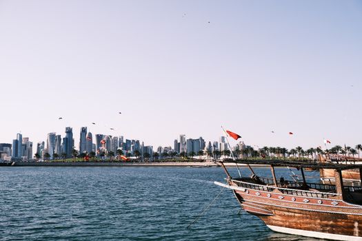 View of Doha skyline with a traditional dhow boat on the waterfront.