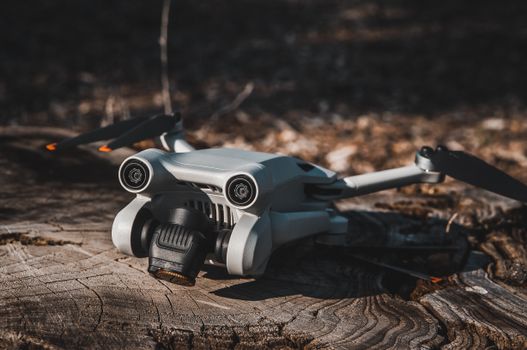 Close-up of a modern drone resting on a tree stump in a forest, highlighting technology in nature.