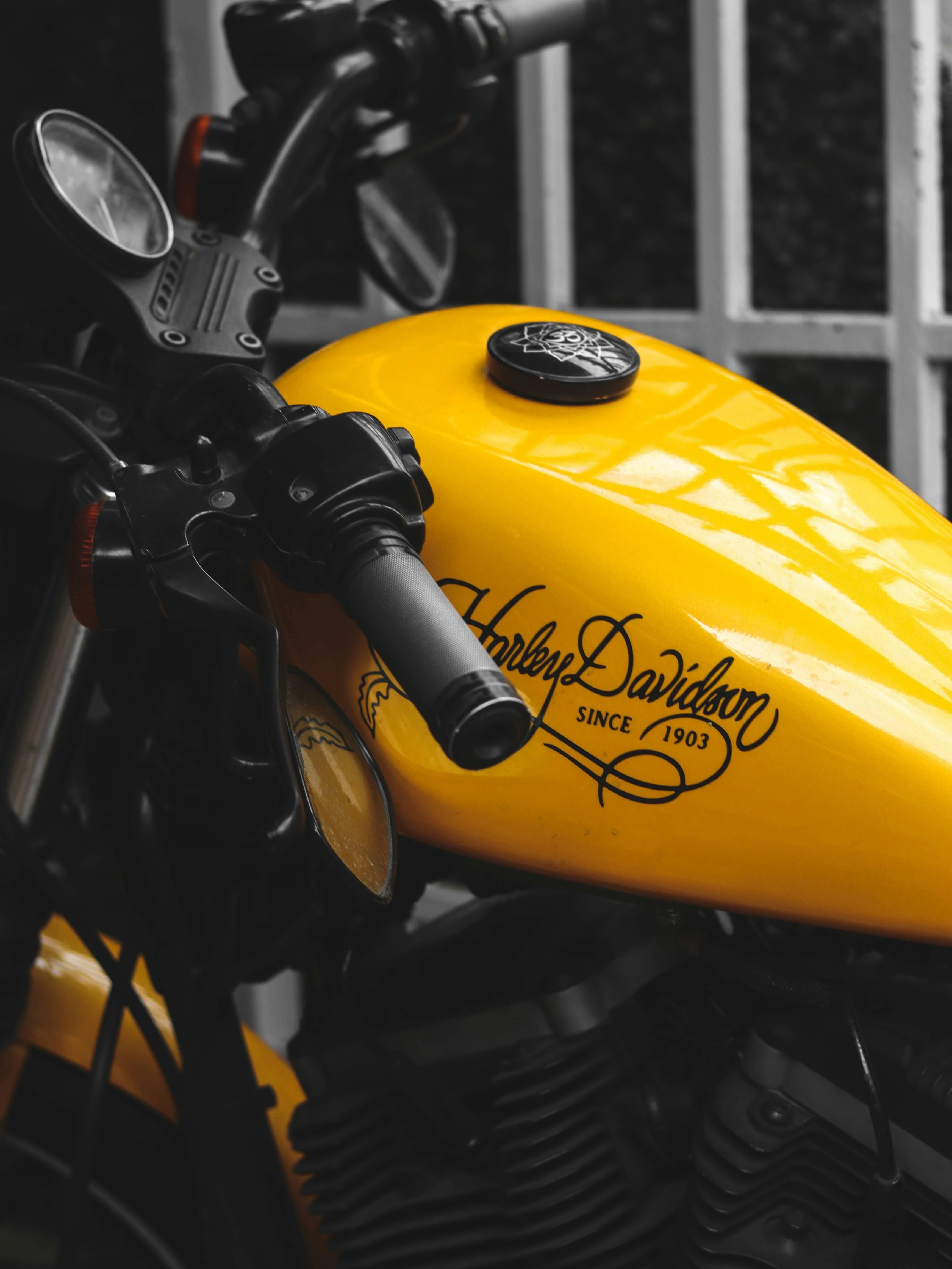 Close-up of a yellow Harley Davidson motorcycle showcasing its sleek tank and handlebars.