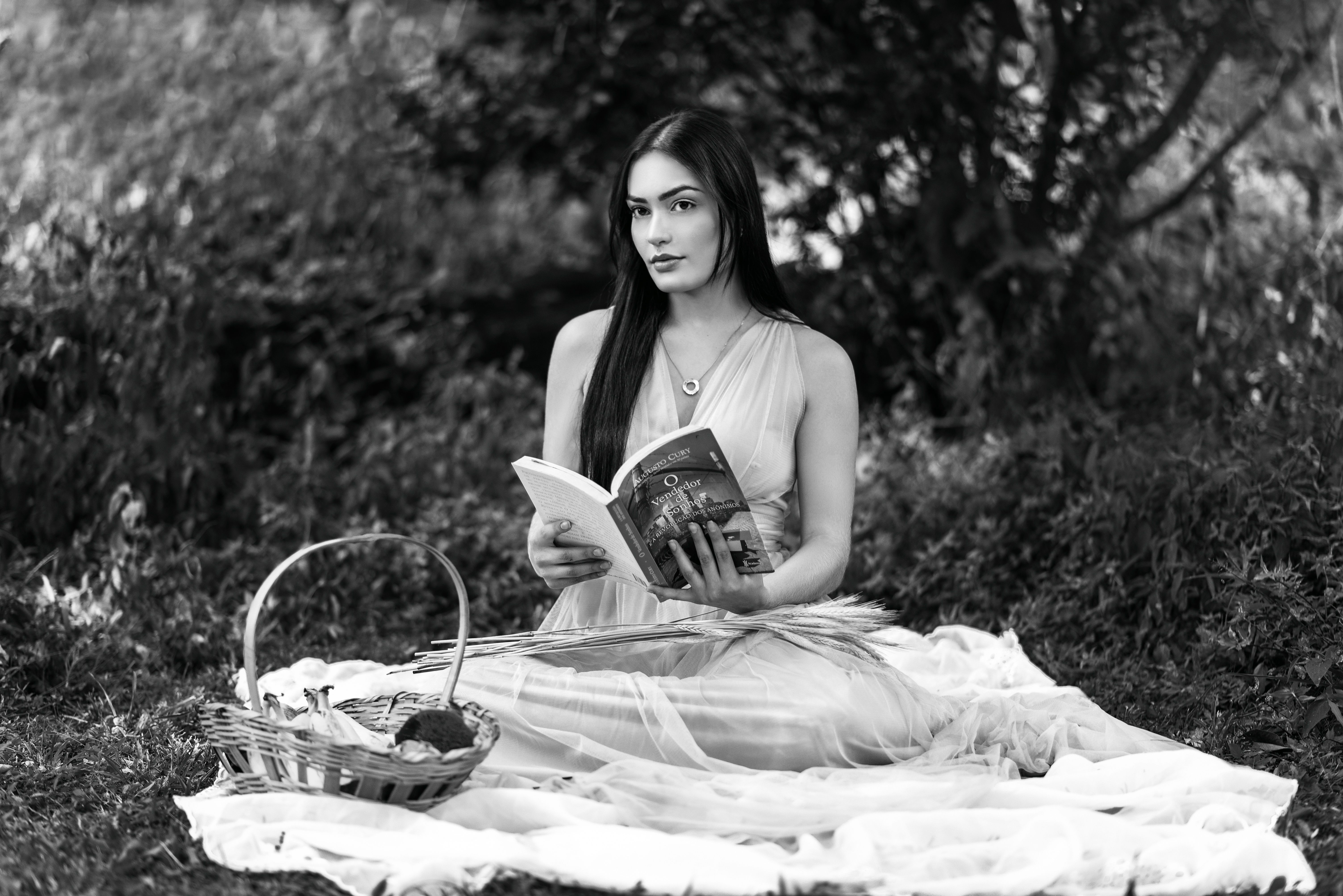 A young woman enjoys a peaceful reading moment on a blanket in Belo Horizonte park.