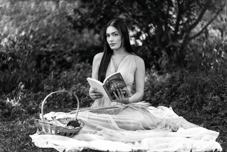 A young woman enjoys a peaceful reading moment on a blanket in Belo Horizonte park.
