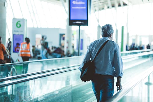 An adult male walking on an airport travelator, captured in a modern and well-lit terminal.