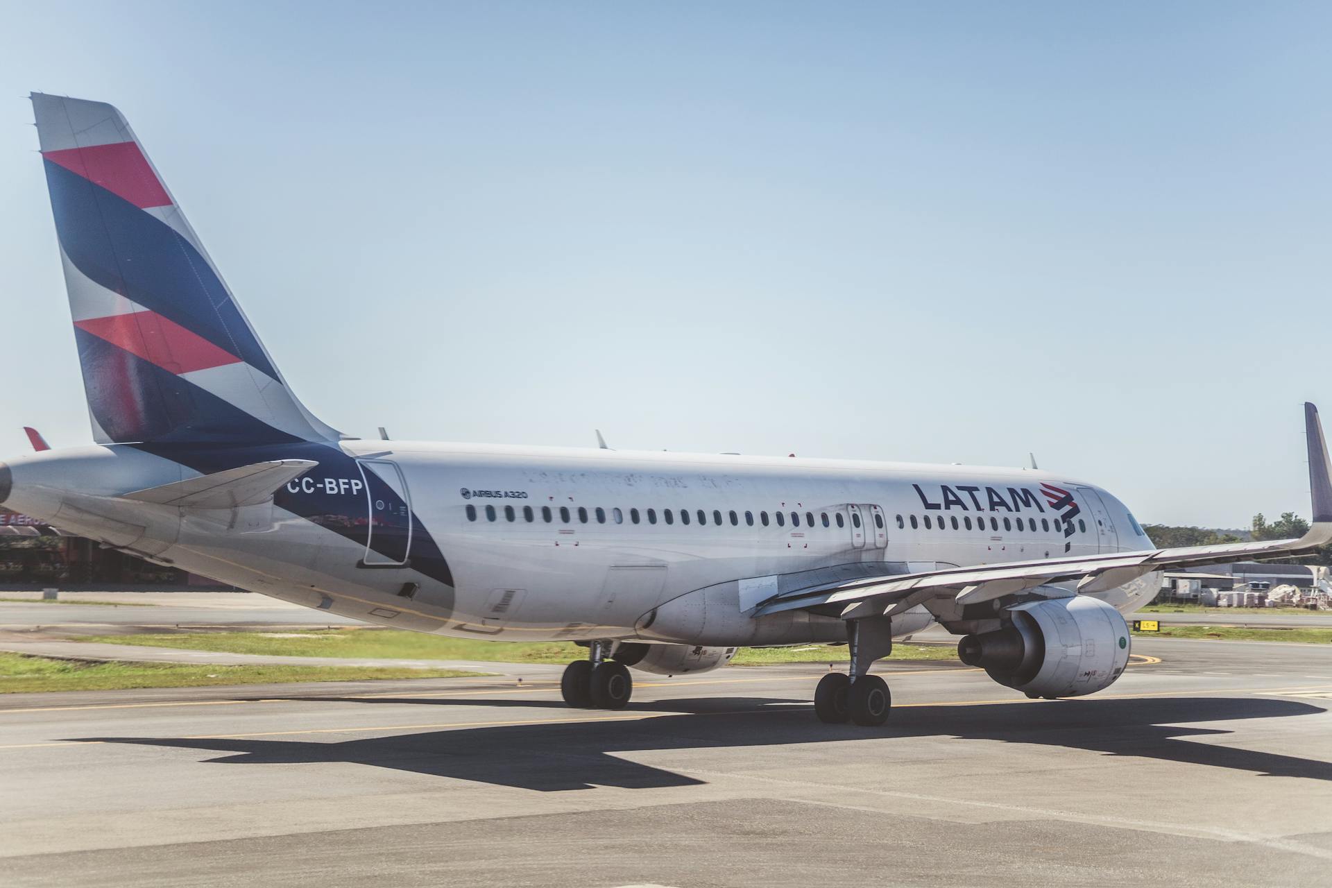 A LATAM Airlines Airbus A320 preparing for takeoff on a sunny airport runway.