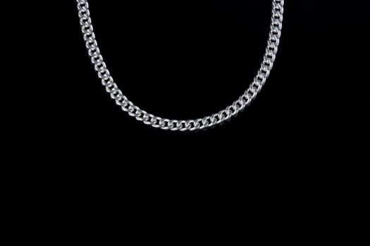 Close-up of a shiny silver necklace showcased against a black background, exuding luxury and elegance.