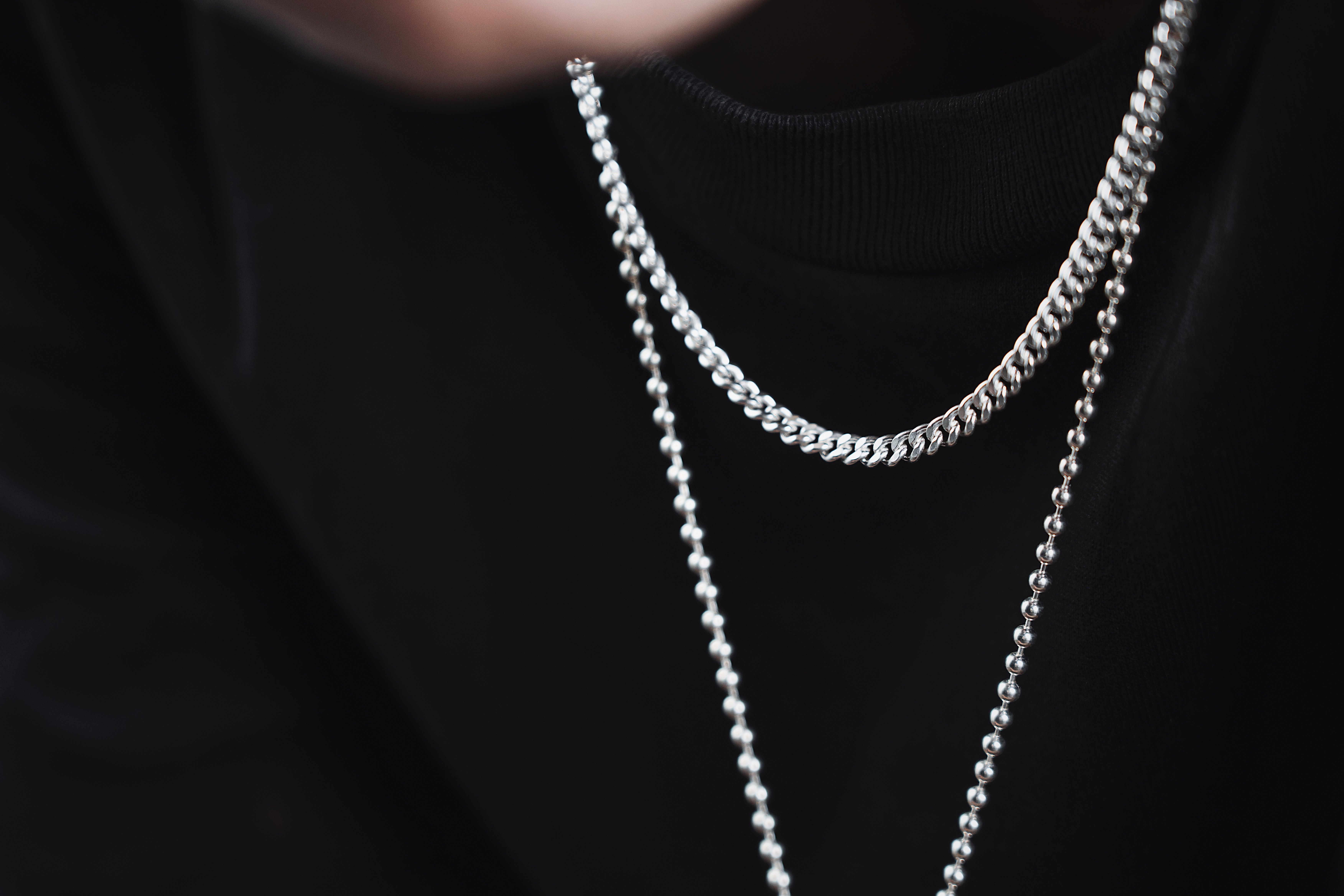Layered men's necklaces with silver chains and symbolic pendants