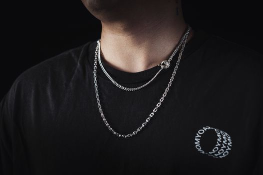 A man wearing stylish silver chains and a black shirt with graphic design.