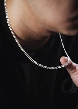 Close-up of a man wearing a polished Cuban link necklace, showcasing modern jewelry style.
